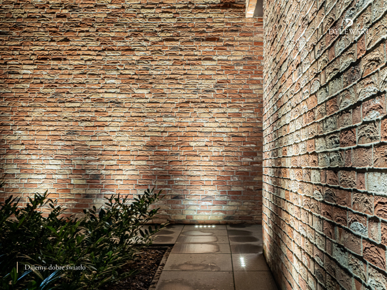 Nowoczesne oświetlenie ogrodu z ceglaną ścianą i światłem podłogowym pod Warszawą zaprojektowane przez DYLEWSKI Lighting