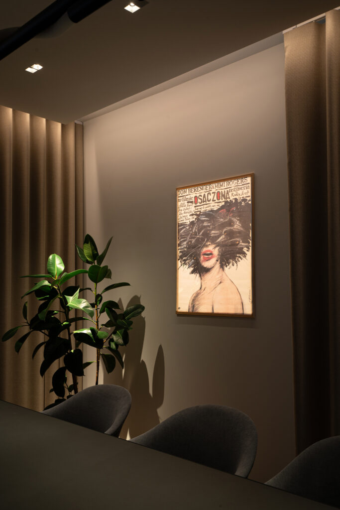 Nowoczesne oświetlenie skandynawskie w salonie, fotel, plakat na ścianie, roślina w doniczce.